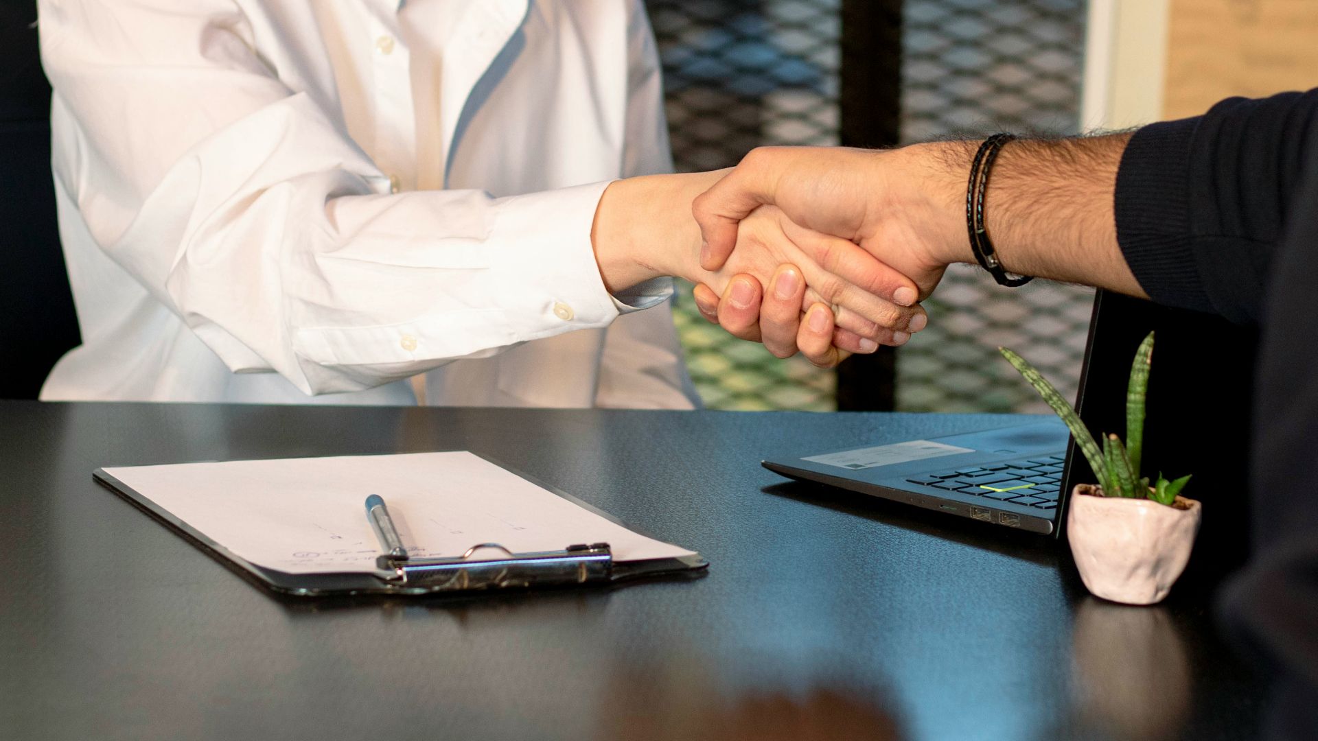 a man and a woman shaking hands in front of a laptop