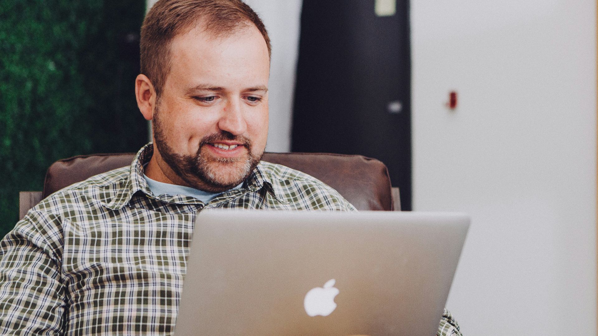 man smiling and using MacBook