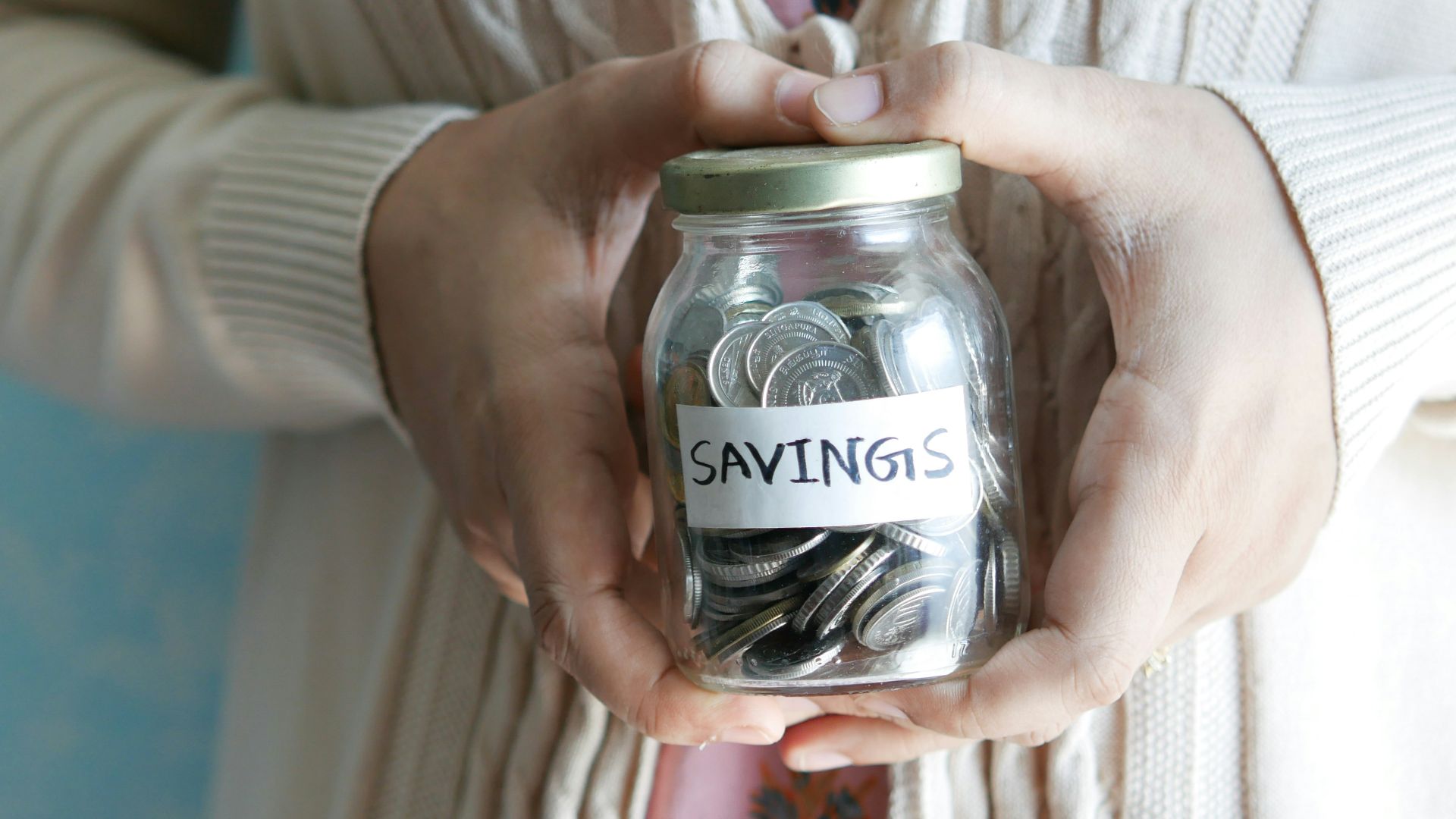 a woman holding a jar with savings written on it
