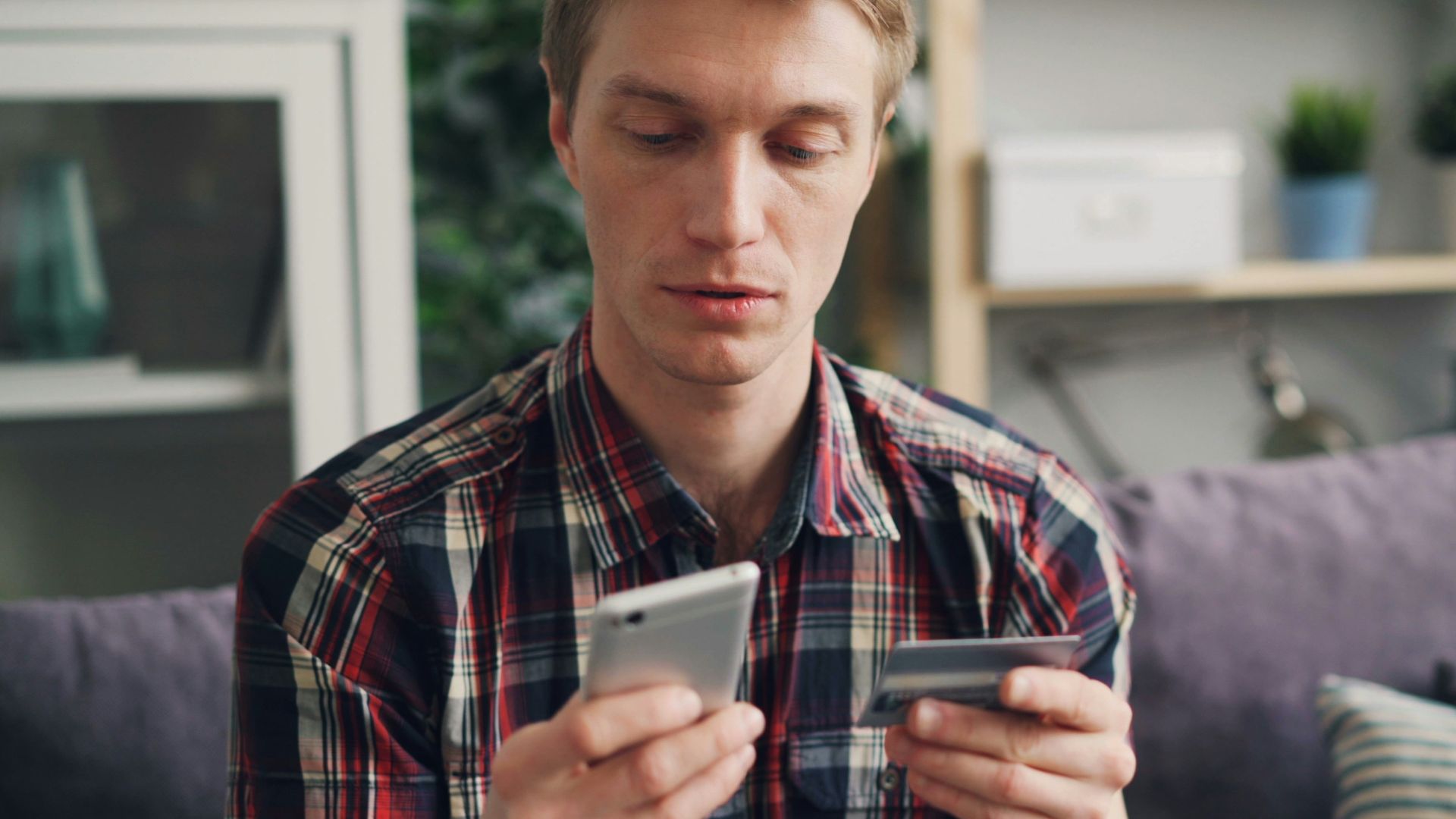 a man sitting on a couch looking at his cell phone