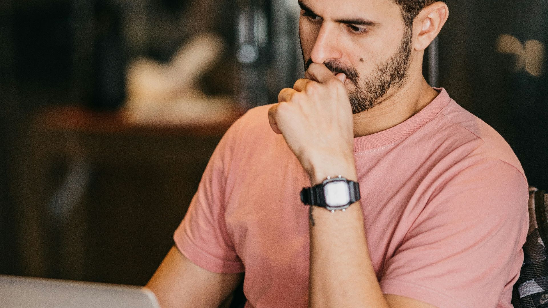 a man sitting at a table with a laptop and a cup