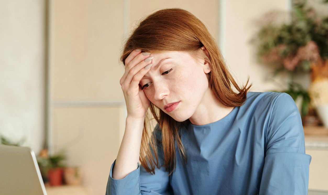 Woman Working with Laptop and Looking at Electric Thermometer