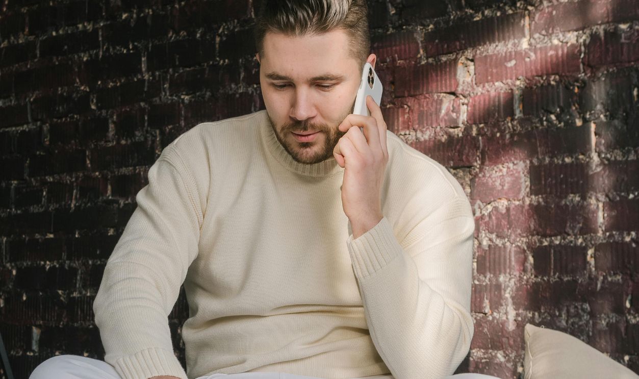 A Man Using a Laptop Holding a Cellphone