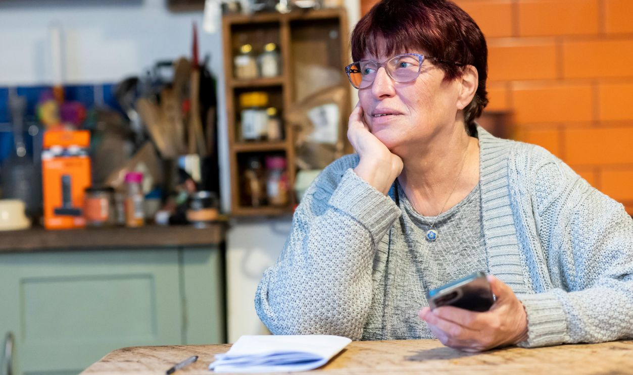 Elderly Woman in Cardigan Sitting at Table