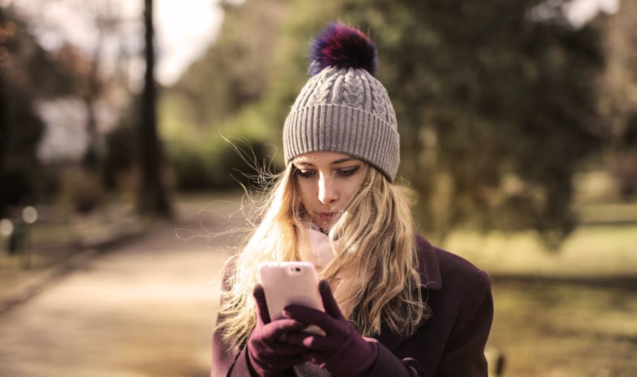 Woman in Violet Coat Holding White Smartphone