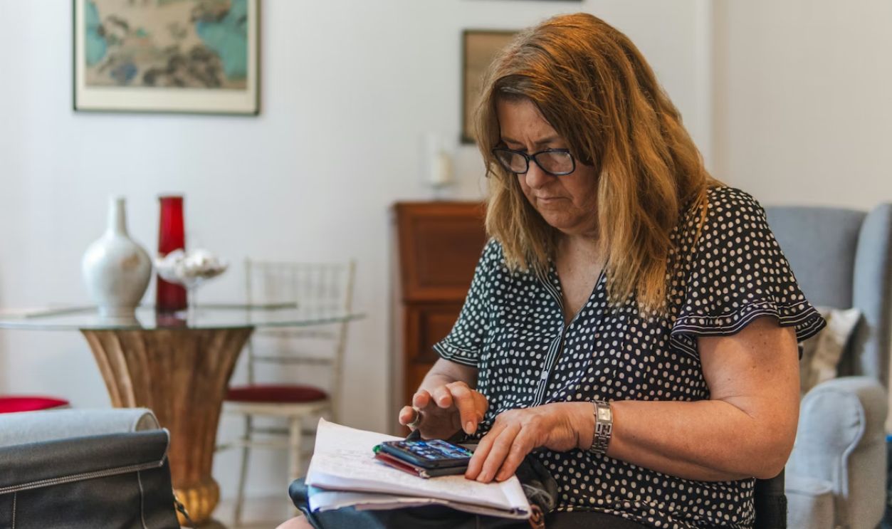 Woman using calculator with papers on table.