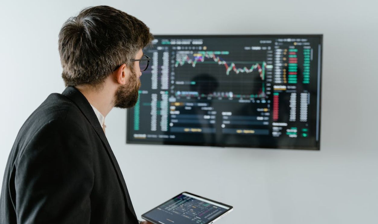 Man in Black Suit Holding a Digital Tablet and Looking At Data On Screen