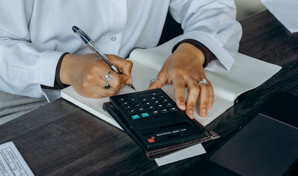 Person in White Long Sleeves Writing on a Notepad