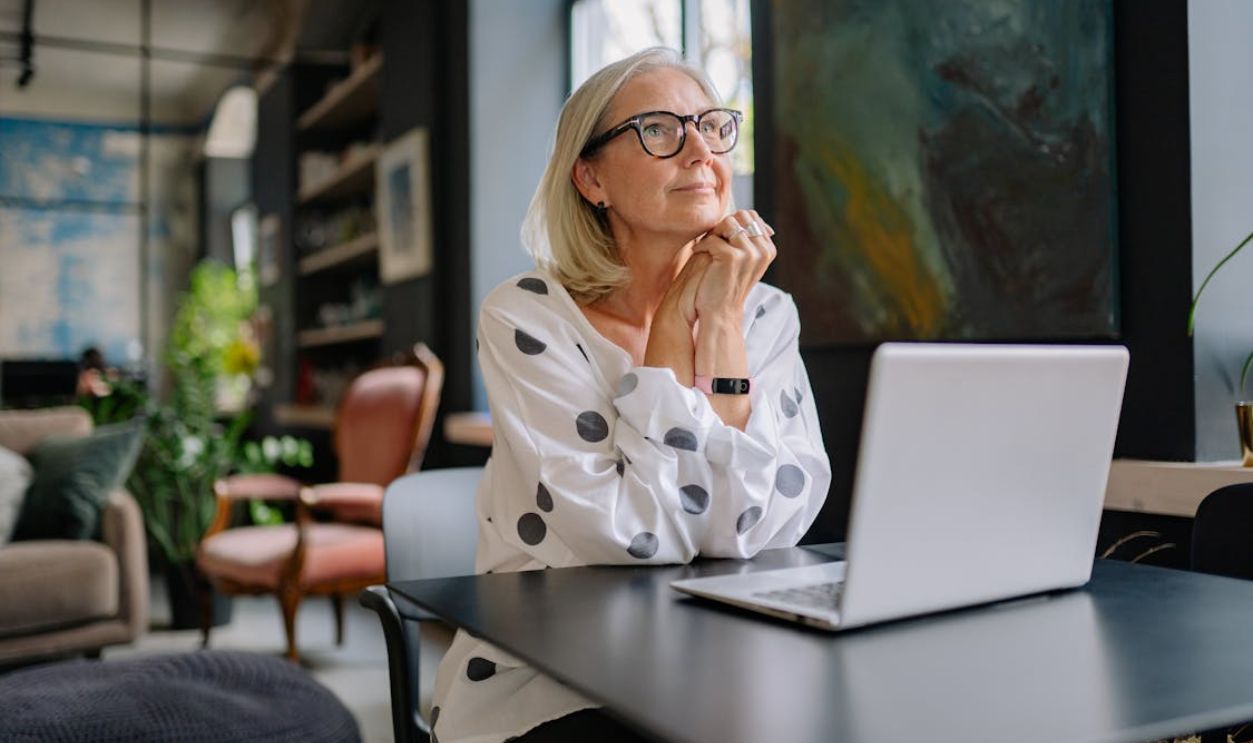 Elderly Woman Sitting at a Table with a Laptop