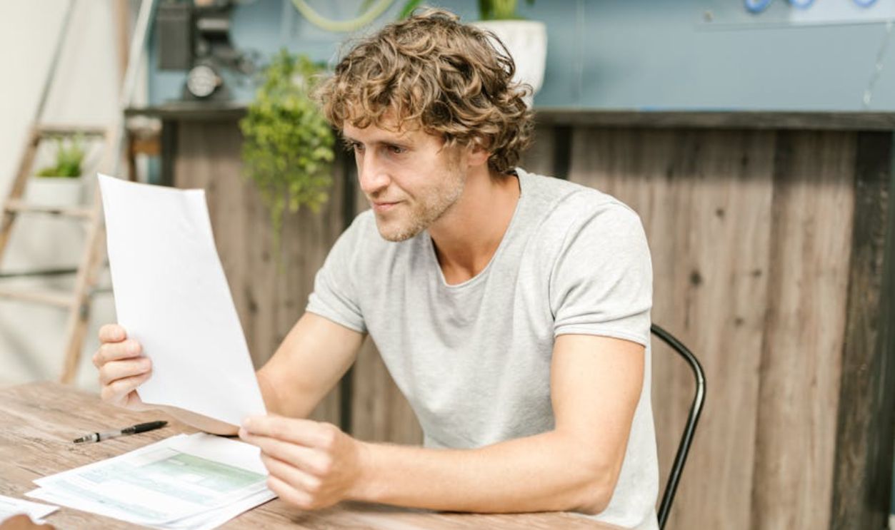 Man in Gray Crew Neck Shirt Reading a Paper