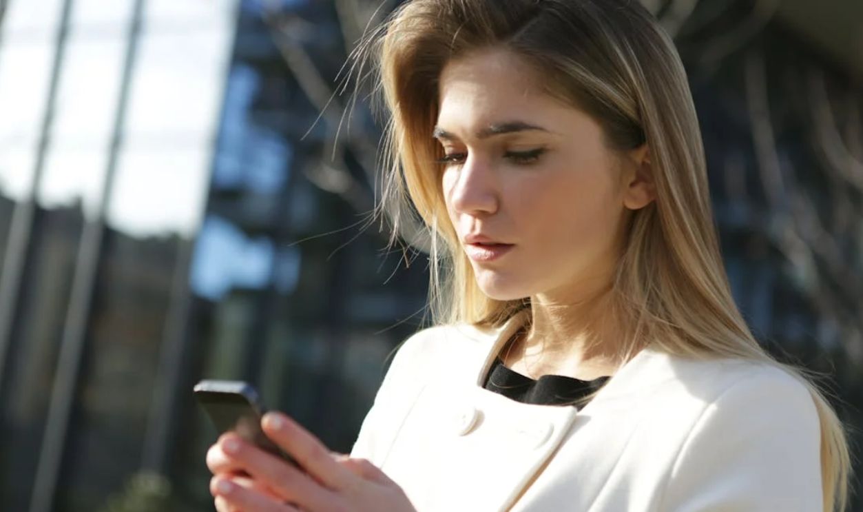 Woman in White Dress Holding Black Smartphone