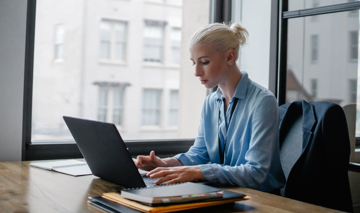 Serious woman typing on laptop in workspace