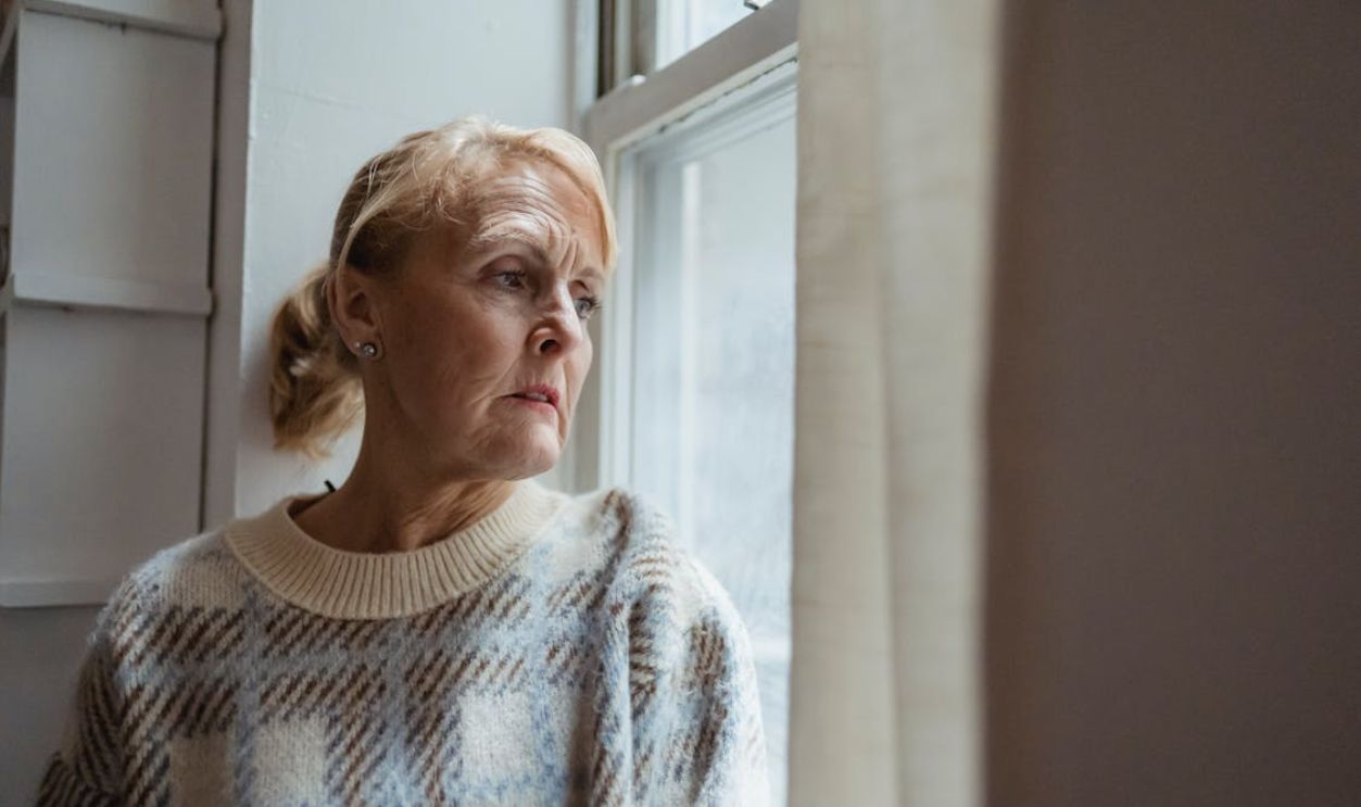 Pondering mature woman looking out window