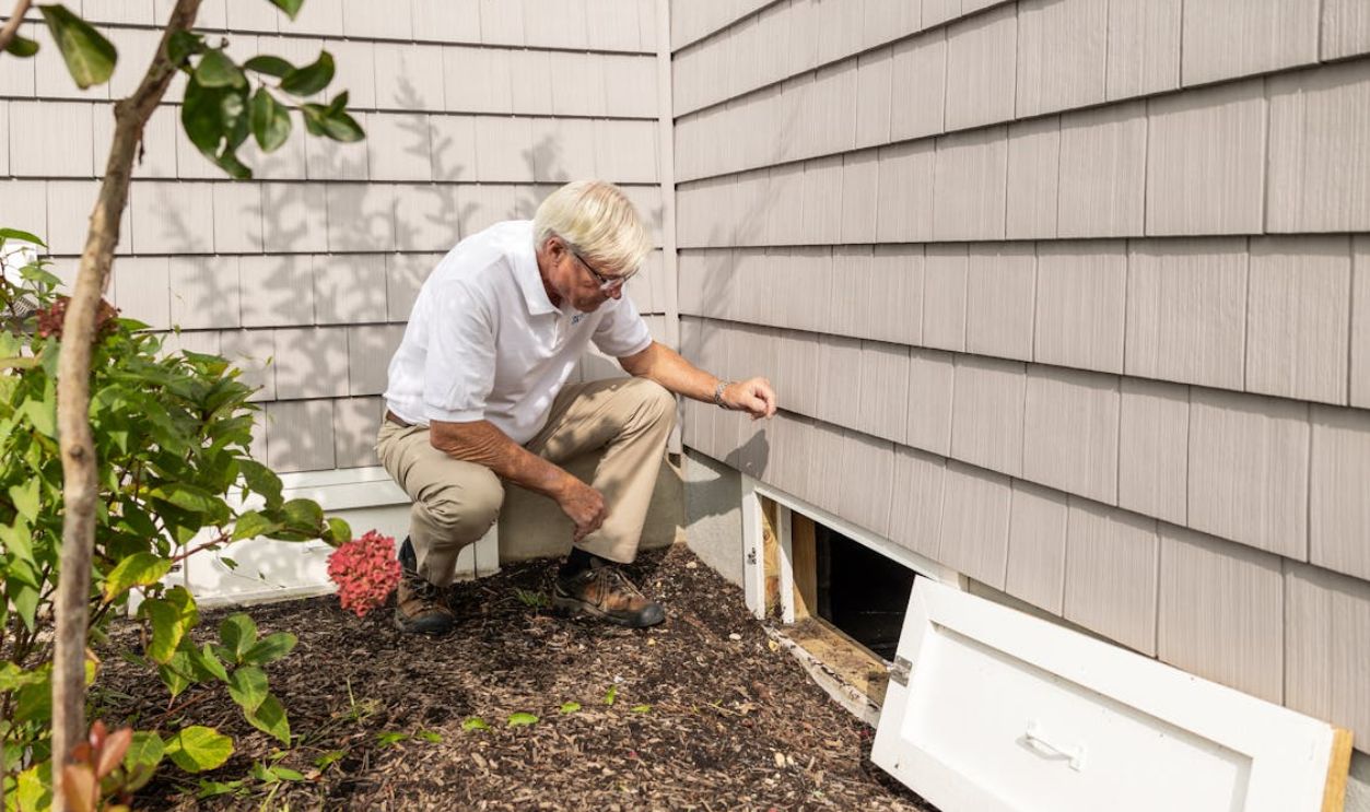 Home inspector examining crawl space outdoors