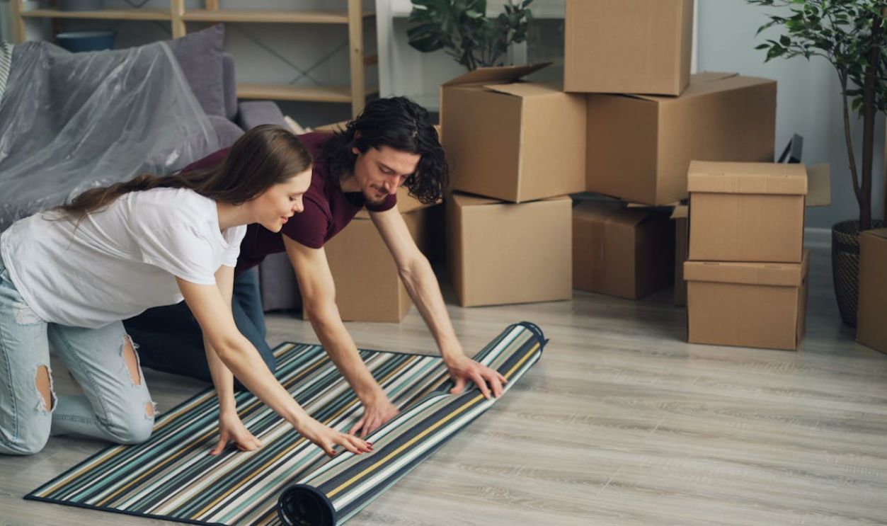 Woman and Man Putting Carpet on Floor