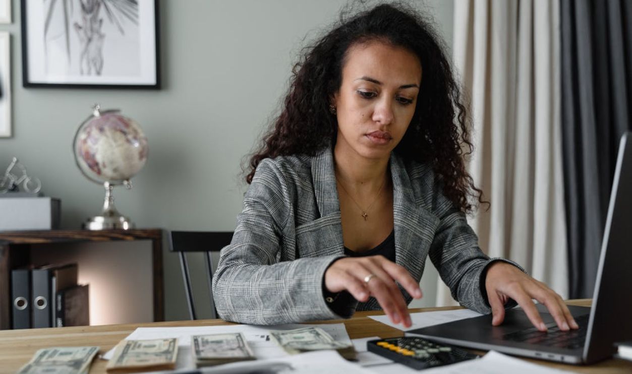 A Woman in Plaid Blazer Using Her Laptop and Mobile Phone