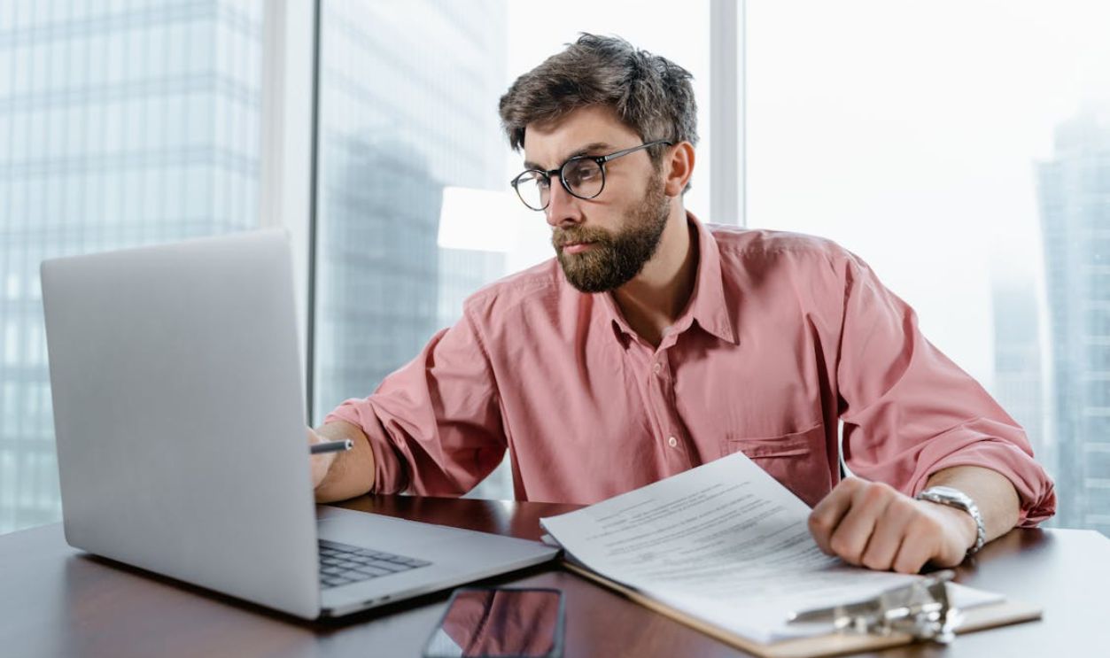 Man in Red Dress Shirt Wearing Black Framed Eyeglasses Using Macbook Air