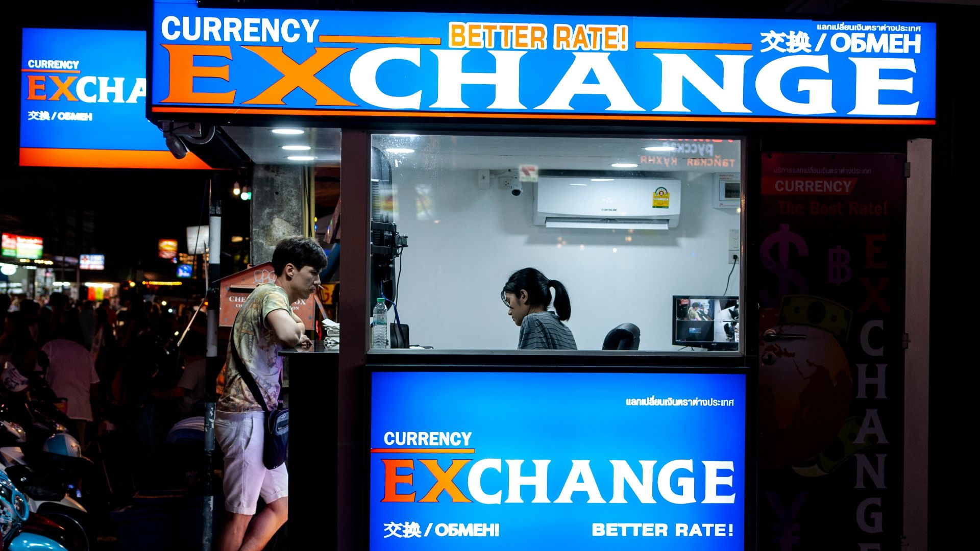 man in gray short standing near counter of currency exchange