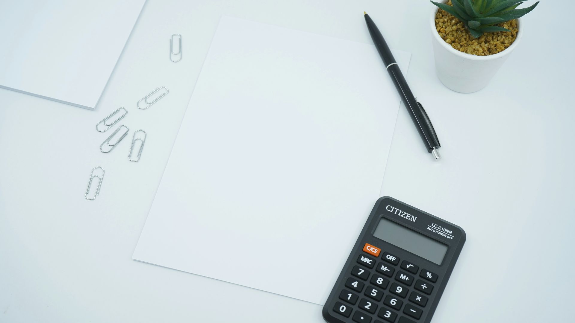 black calculator beside black pen on white printer paper