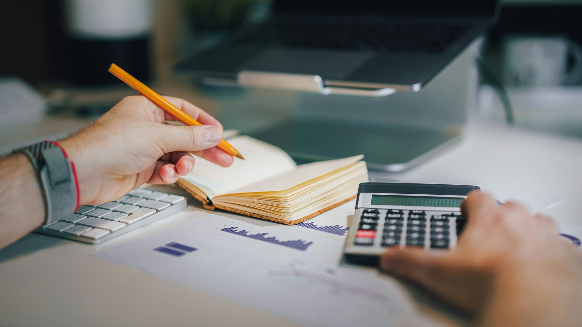 a person sitting at a desk with a calculator and a notebook