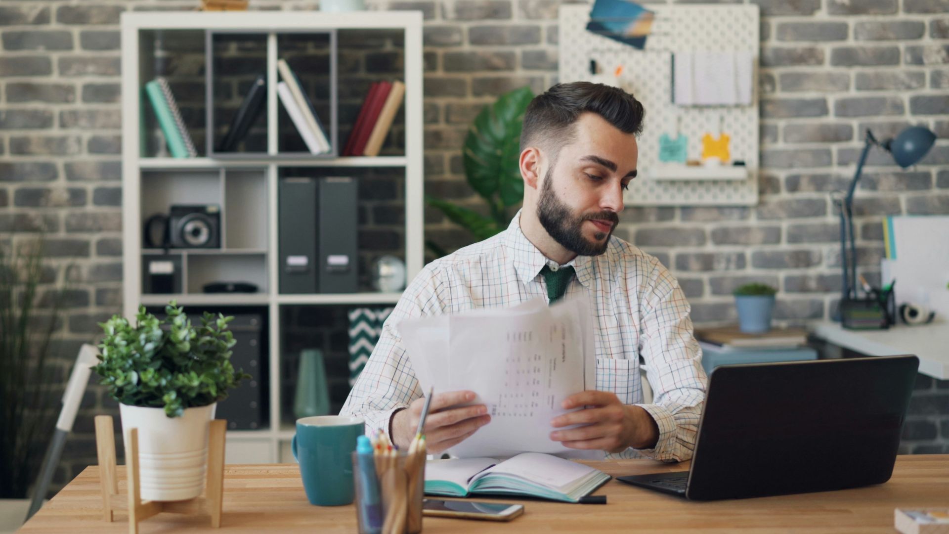a man sitting at a desk with a laptop and papers