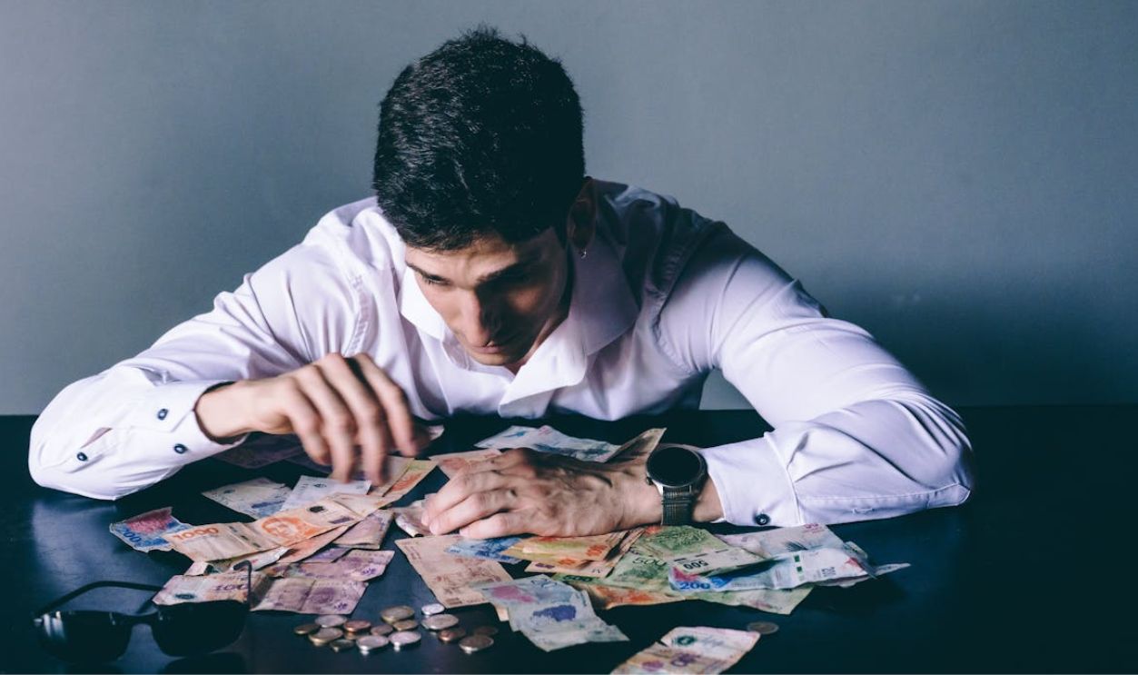 Man Counting International Currency on Desk