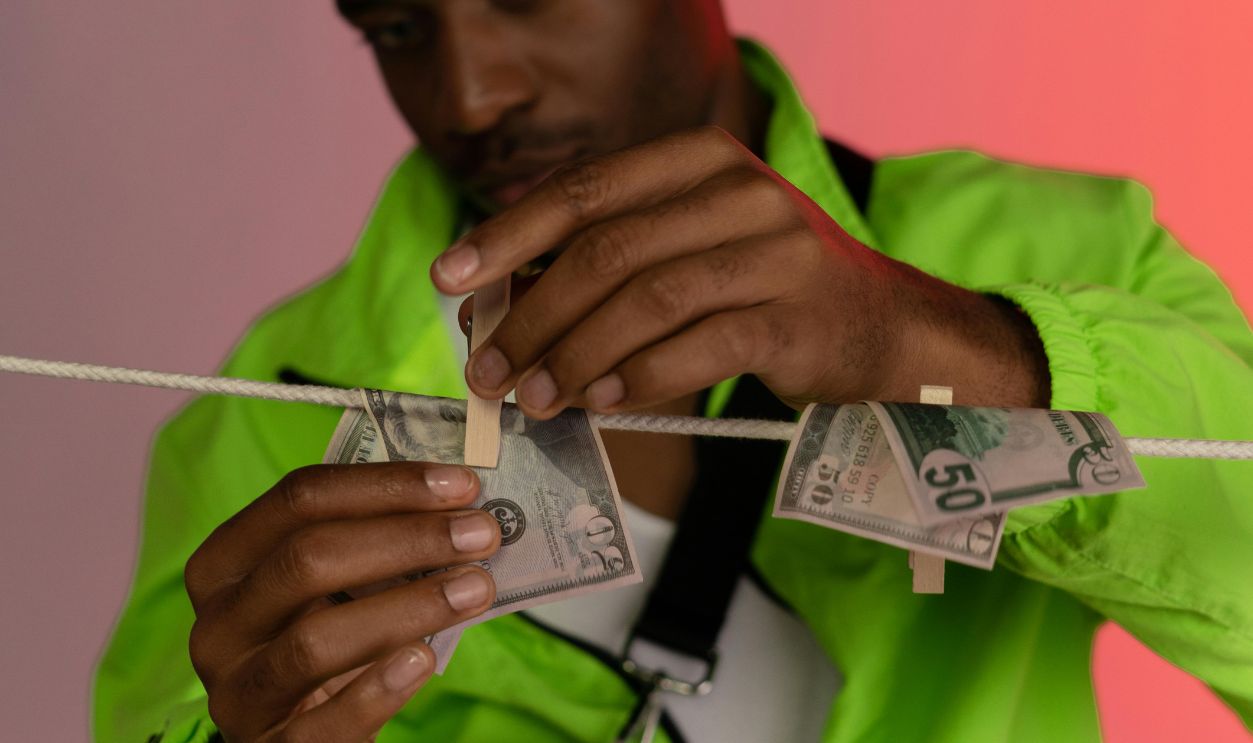 Man in Green Jacket Hanging Wet Banknotes on the Clothes Line