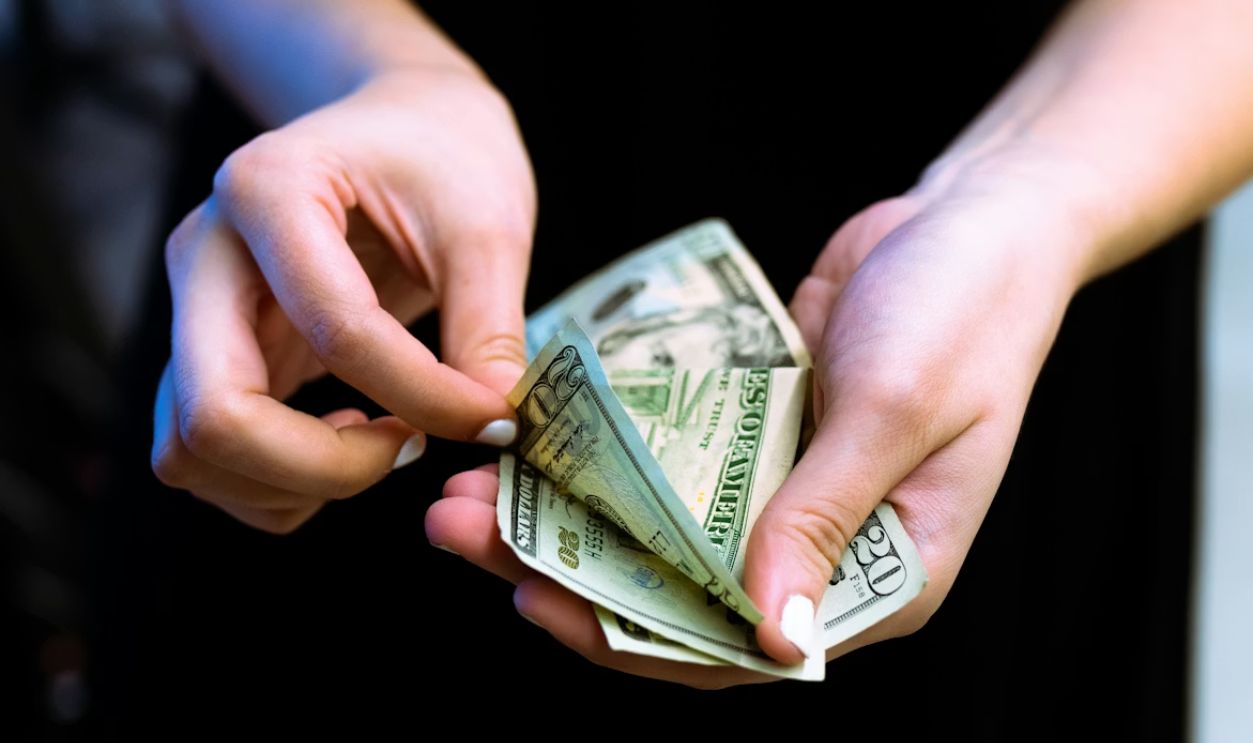 Customer depositing a full stack of cash at a bank teller