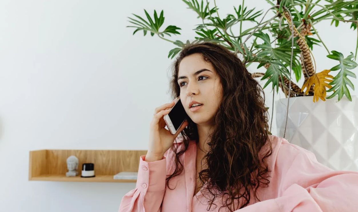 A Curly-Haired Woman in Pink Long Sleeves Having a Phone Call