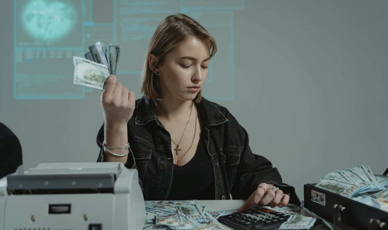 A Woman Sitting at a Table Accounting a Sum of Cash