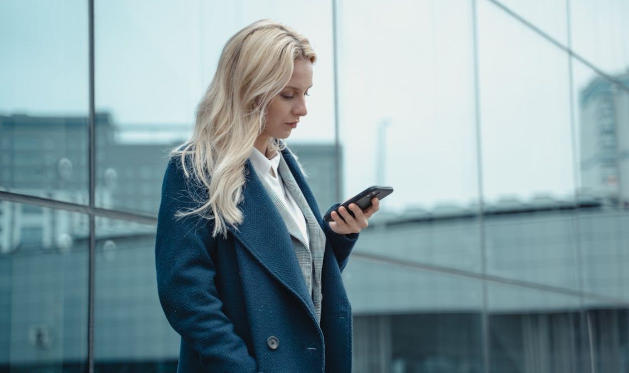 A Woman in a Blue Coat Using Her Phone