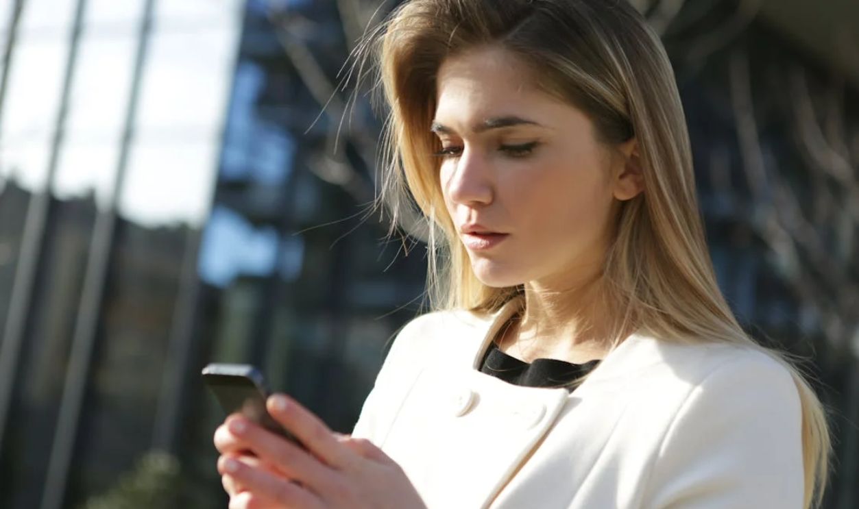 Woman in White Dress Holding Black Smartphone