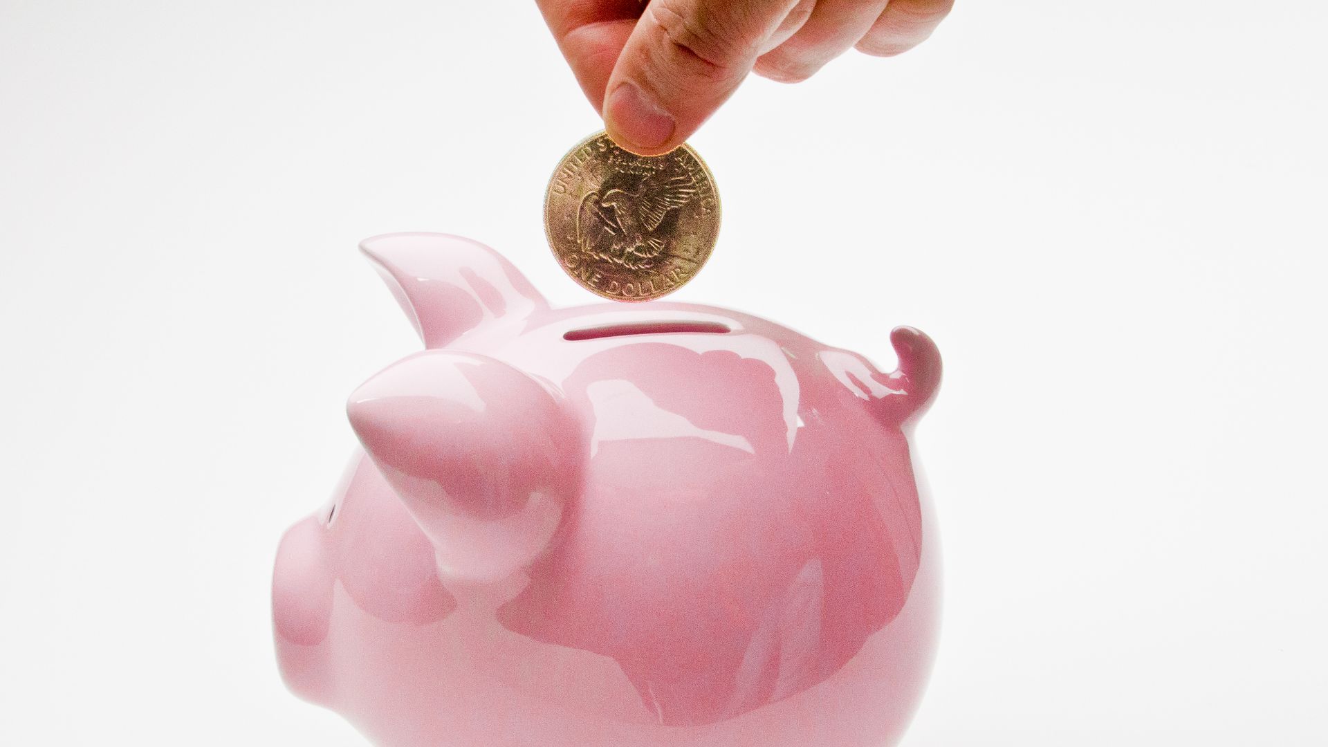 Hand Putting Deposit Into Piggy Bank, shot for SeniorLiving.Org