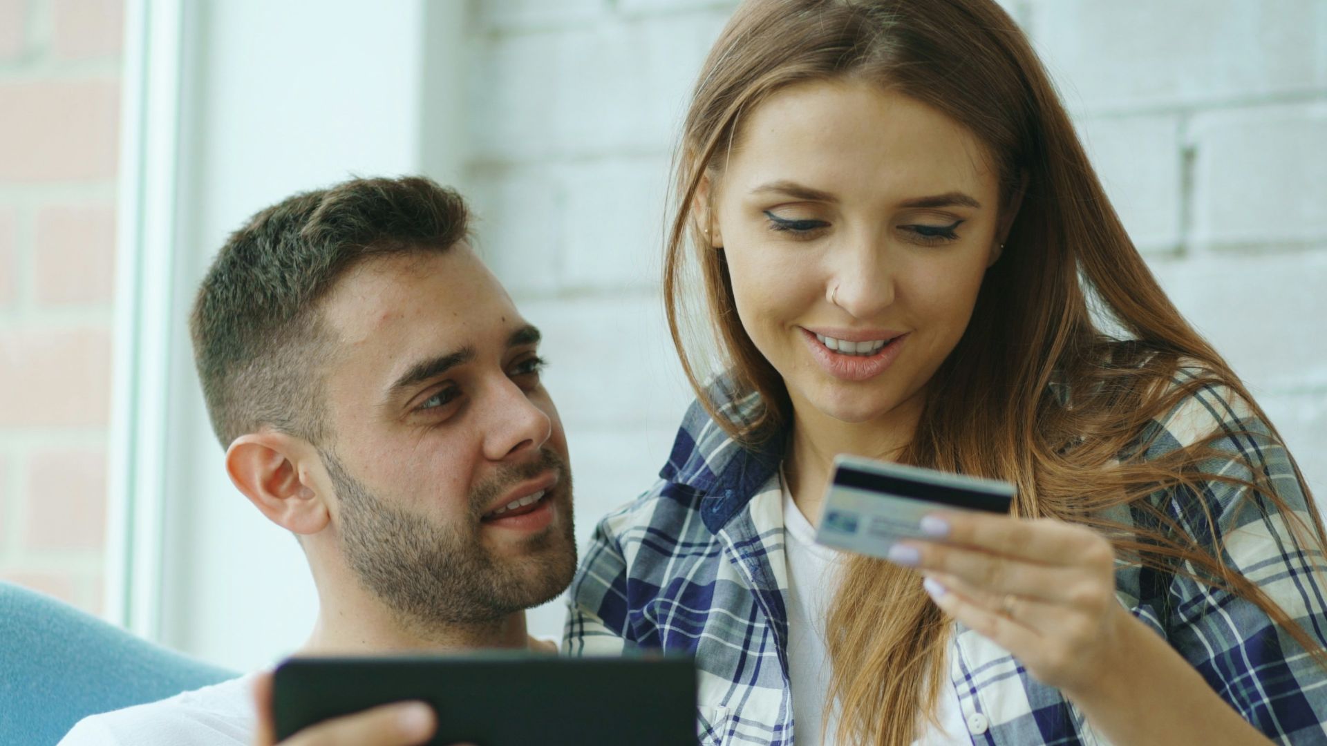 Couple using tablet and credit card for online shopping.