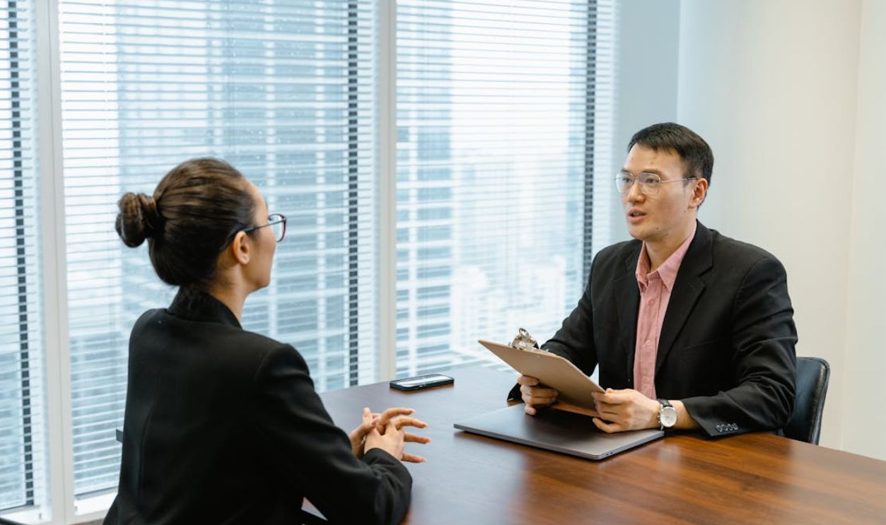 Man in Glasses Holding a Folder While Talking to a Woman in Suit
