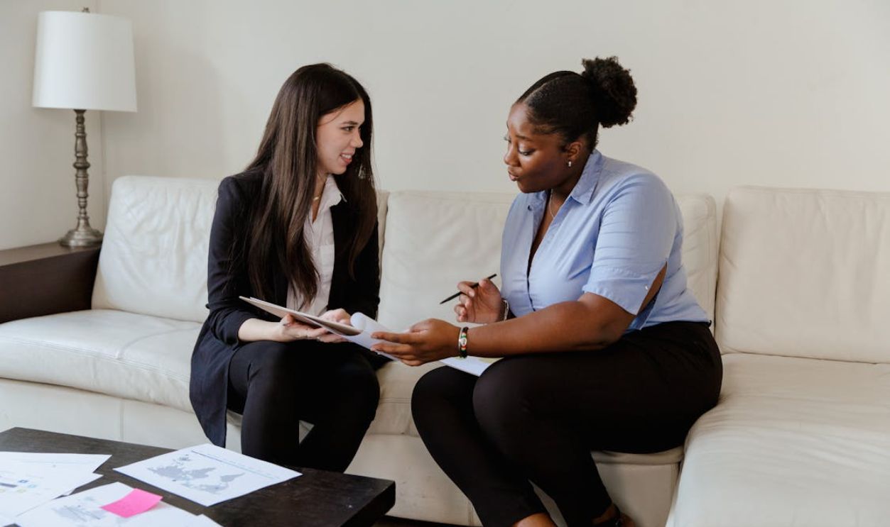 Women Sitting on White Couch Discussing