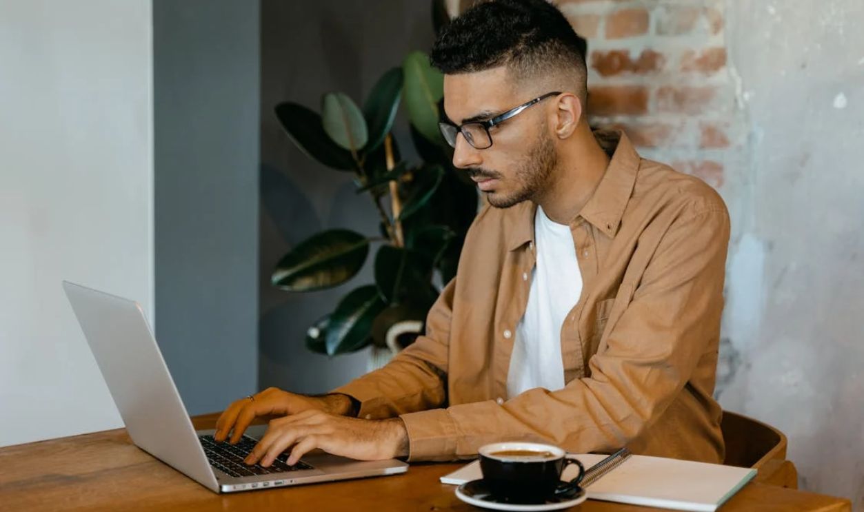 Man in Brown Dress Shirt Typing on a MacBook Pro
