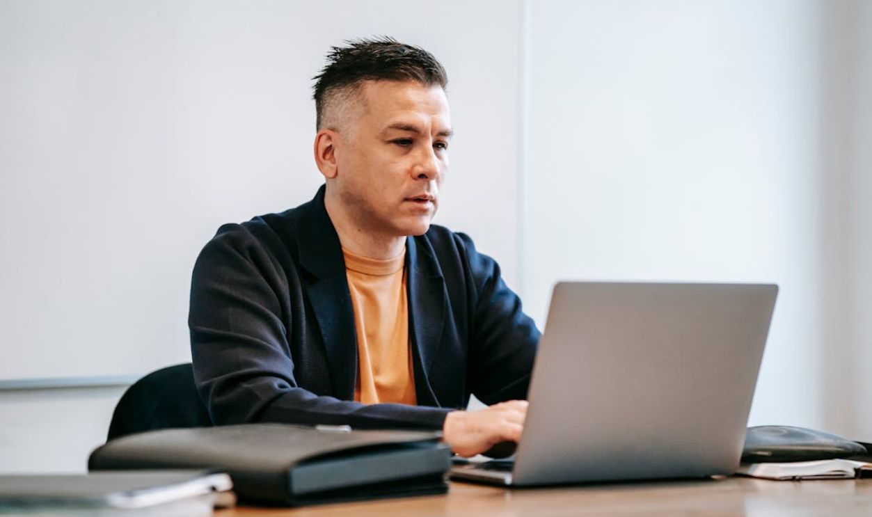Photo Of Man Using HIs Grey Laptop