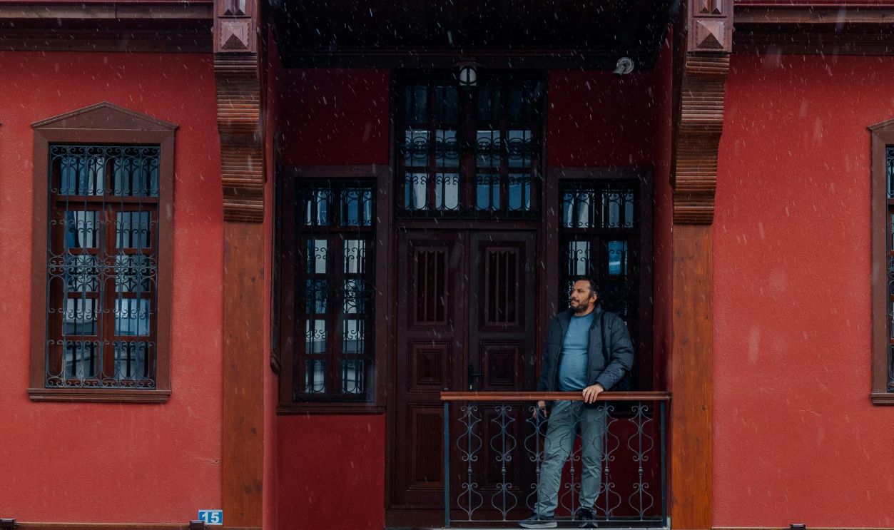 Charming Red House with Man on Balcony in Snow