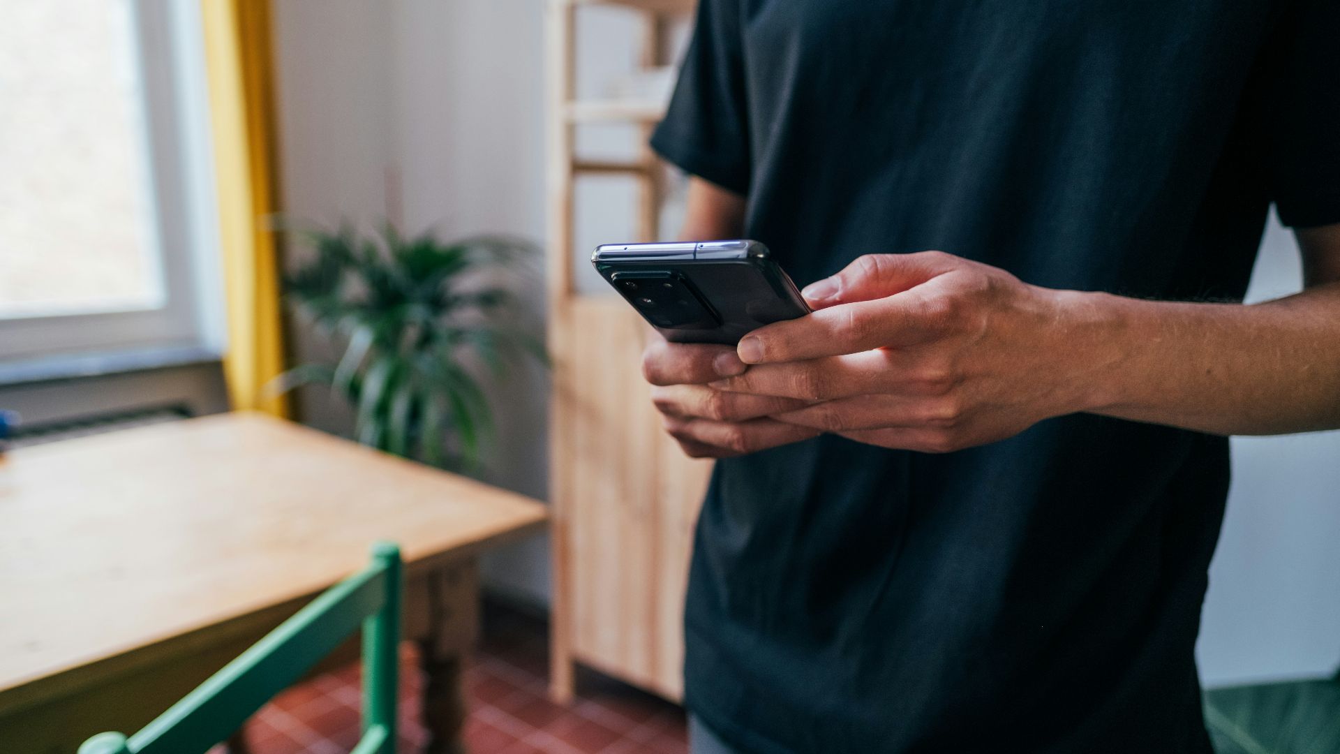 person in blue long sleeve shirt holding black smartphone