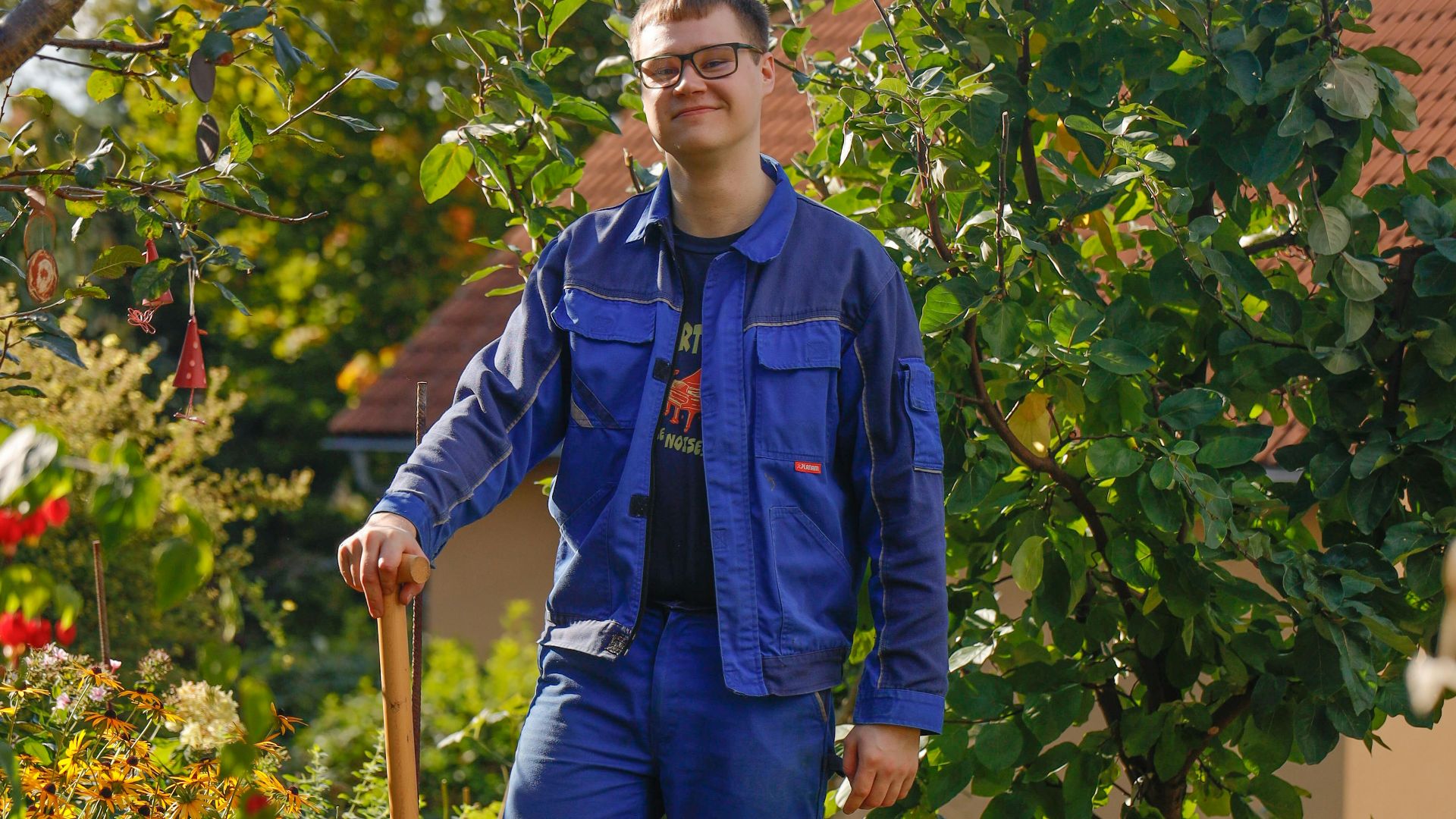Man in blue work clothes holding shovel in garden