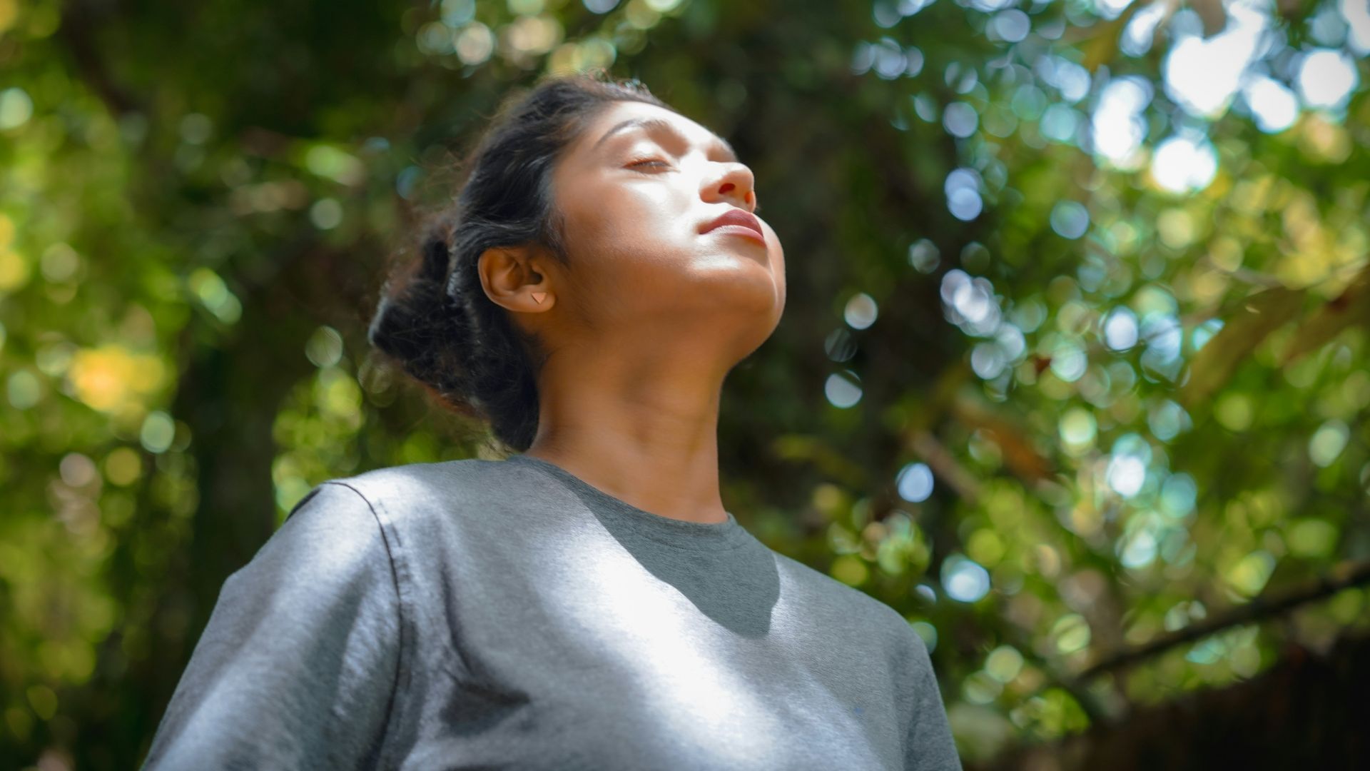a woman standing in front of a tree with her eyes closed