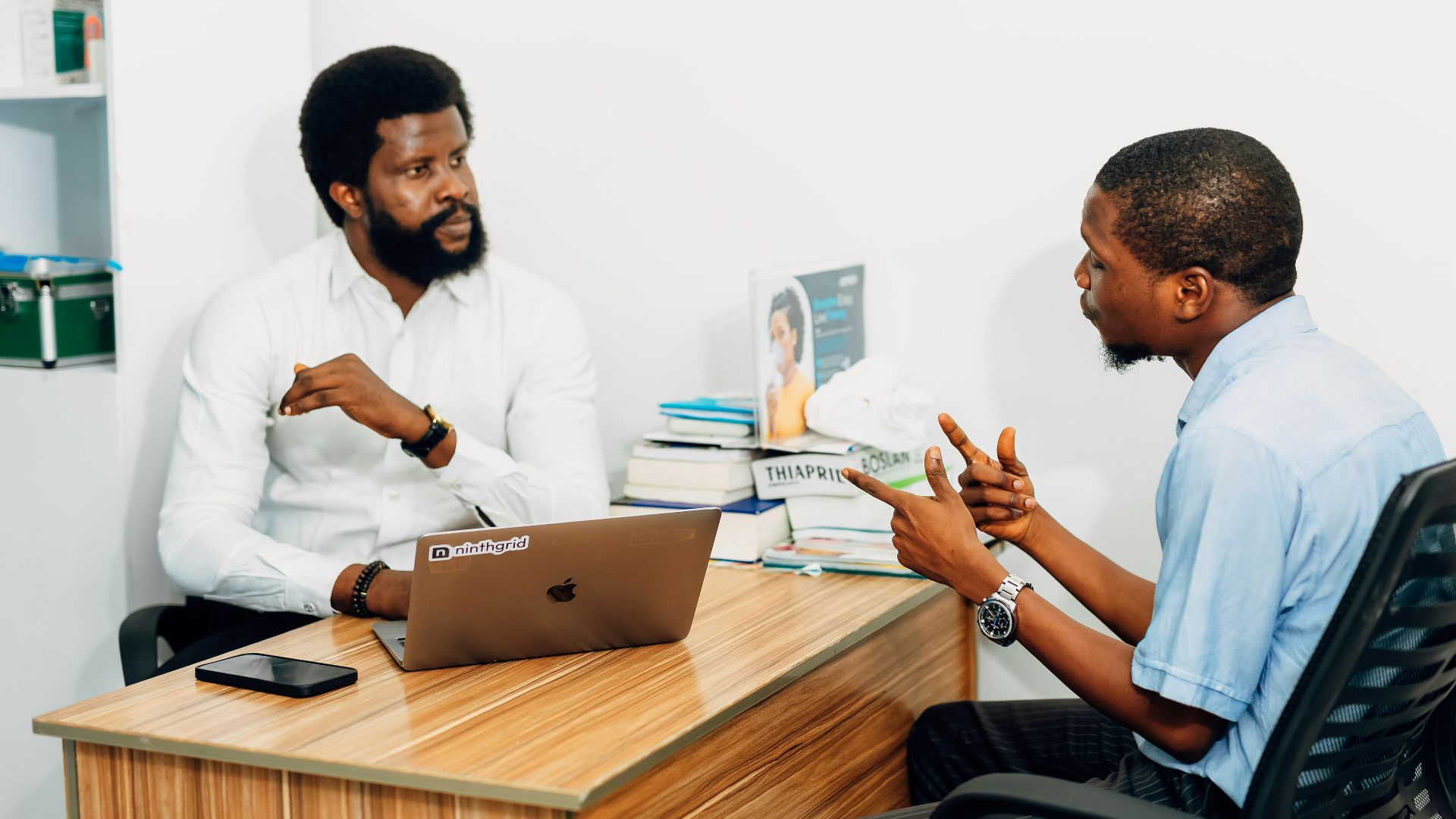 Two men sitting at a desk talking to each other