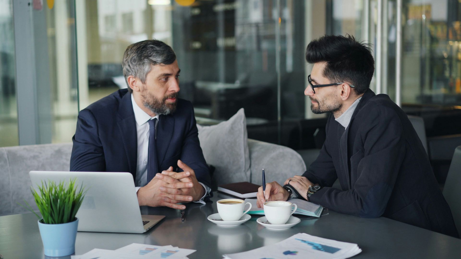 two men sitting at a table having a conversation