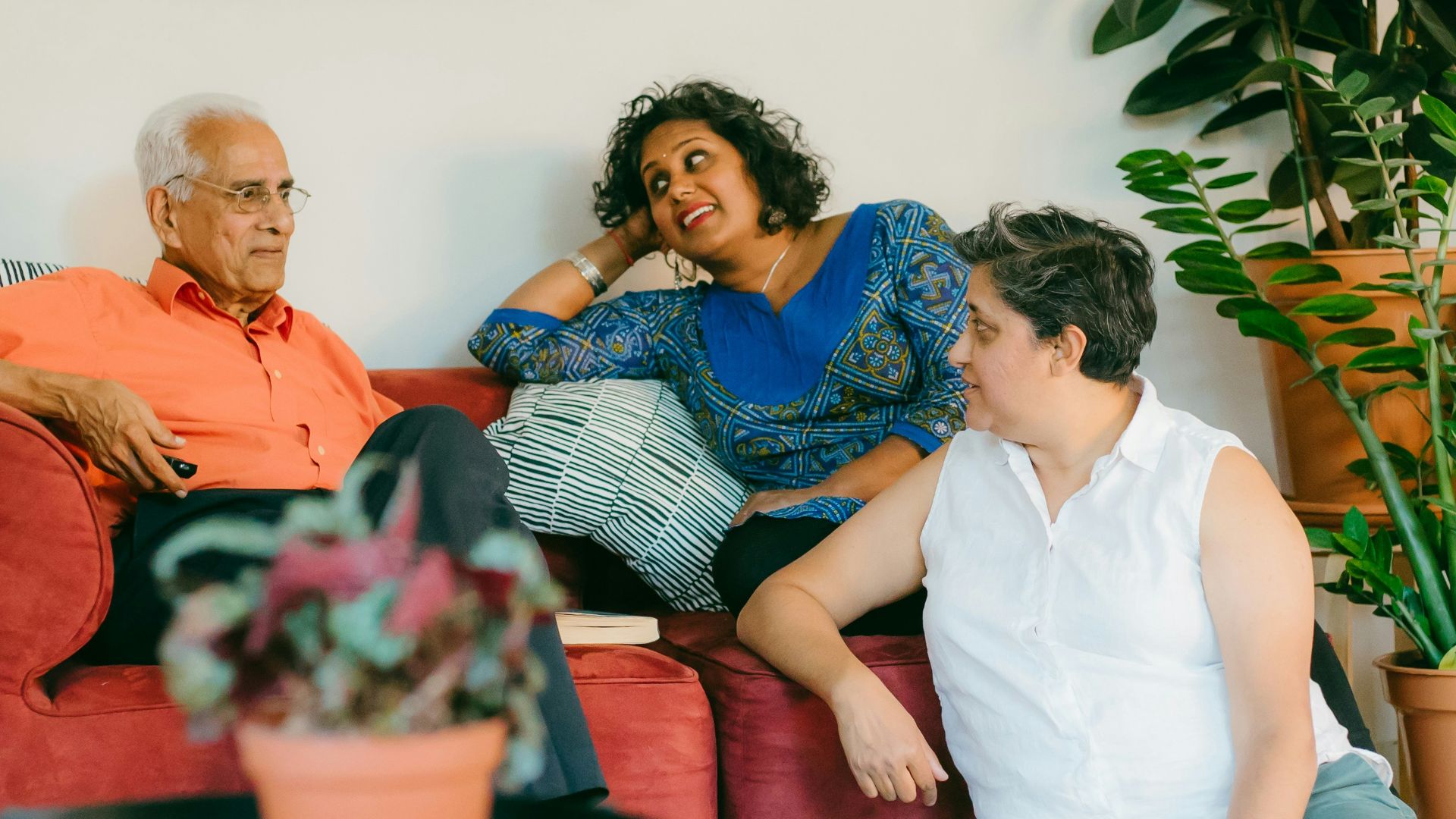 a woman sitting on top of a red couch next to a man