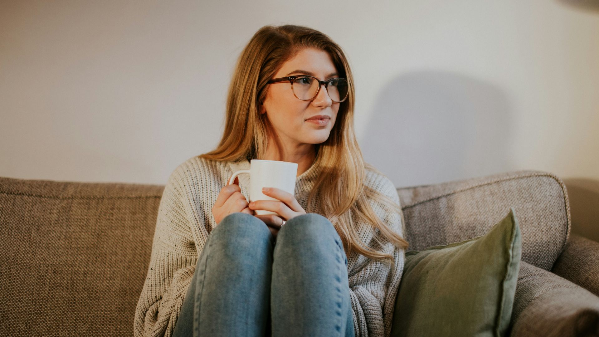 woman in blue denim jeans sitting on gray sofa
