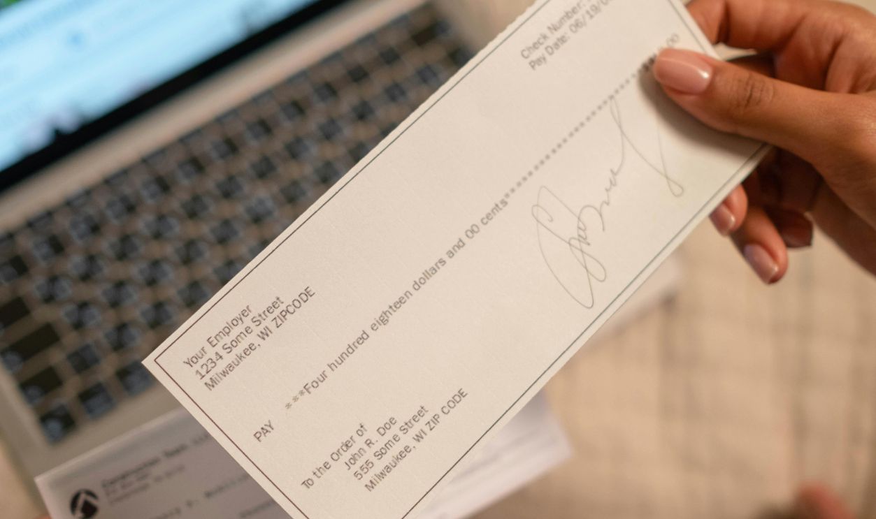 A Person's Hand Holding a Cheque
