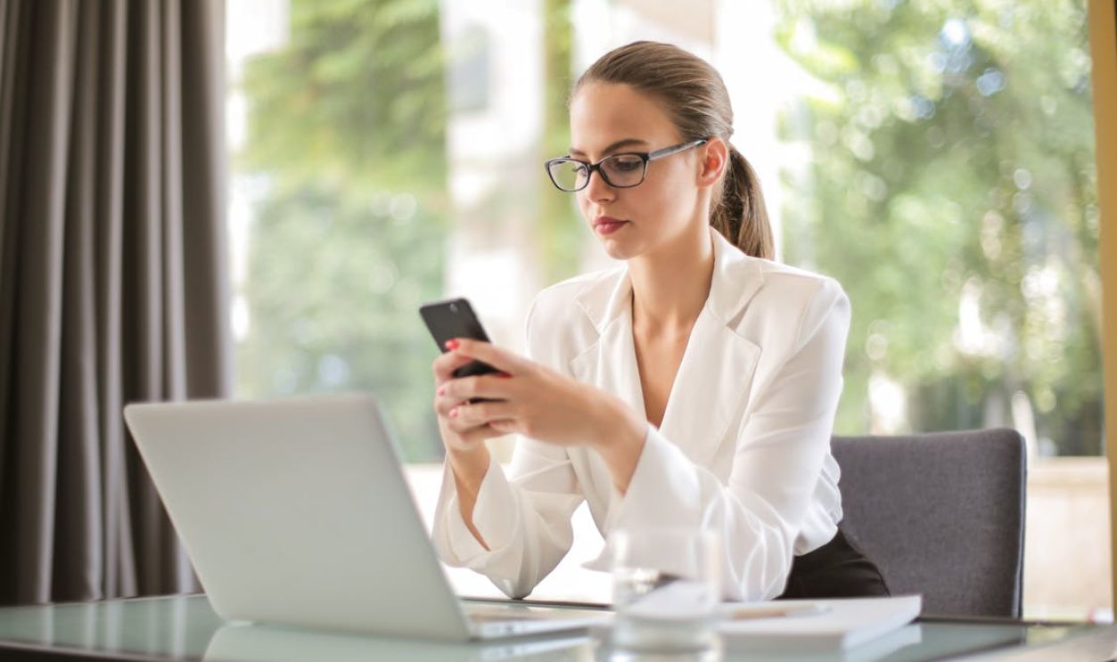 Serious businesswoman using smartphone in workplace