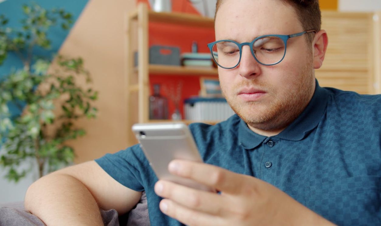Man Using Smartphone in Bright Indoor Setting