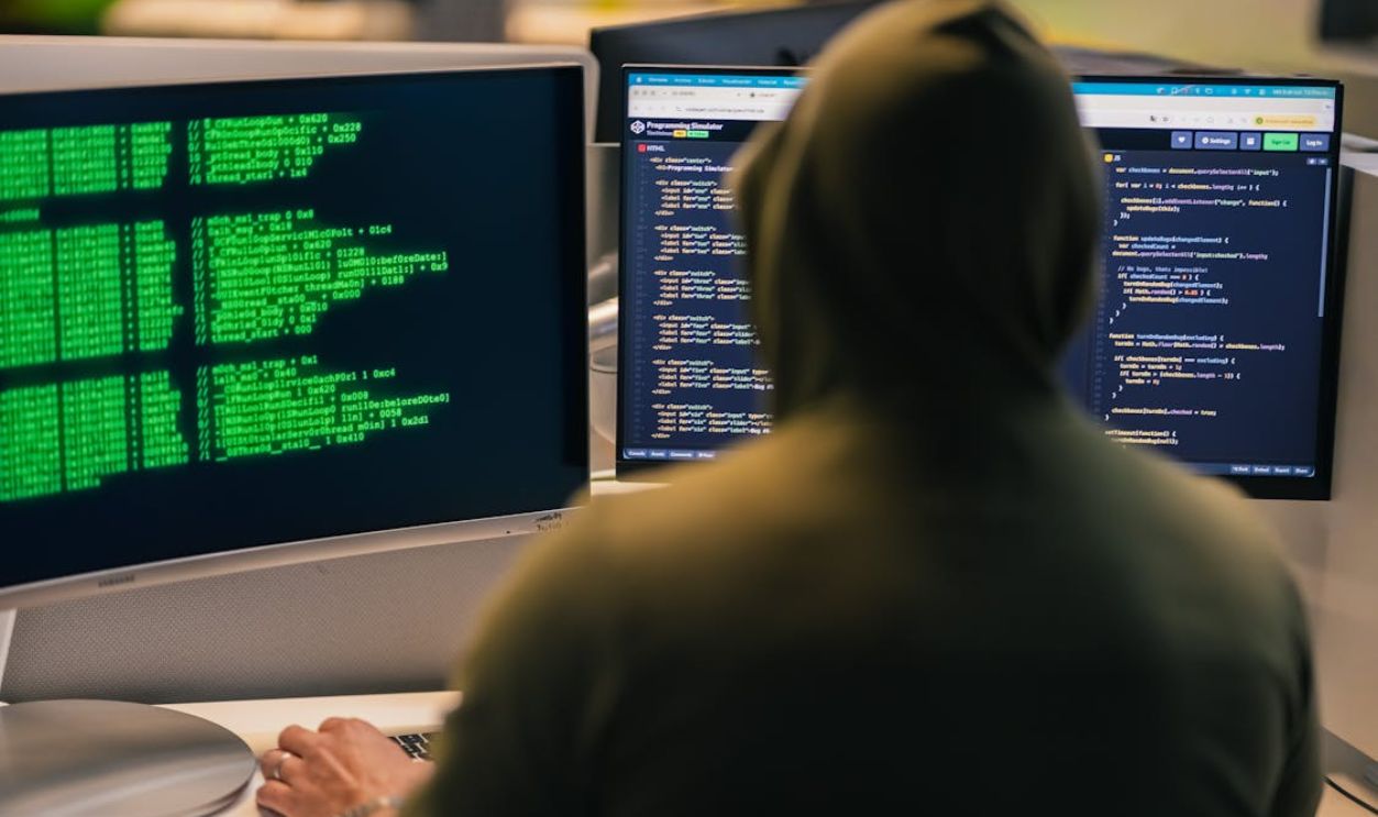 Hacker Coding on Multiple Monitors at Night